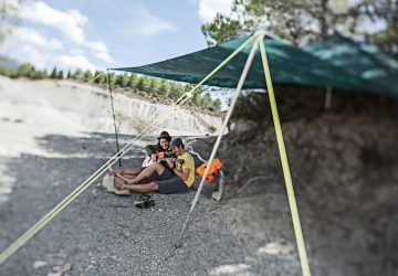 All-Round Talent: The Tarp 4 Tarp Tips - A young couple is sitting in the sun under a tarp. He is playing guitar.
