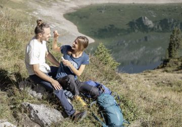 Hiking equipment - the basic items 4 Couple taking a break from hiking near a mountain lake.