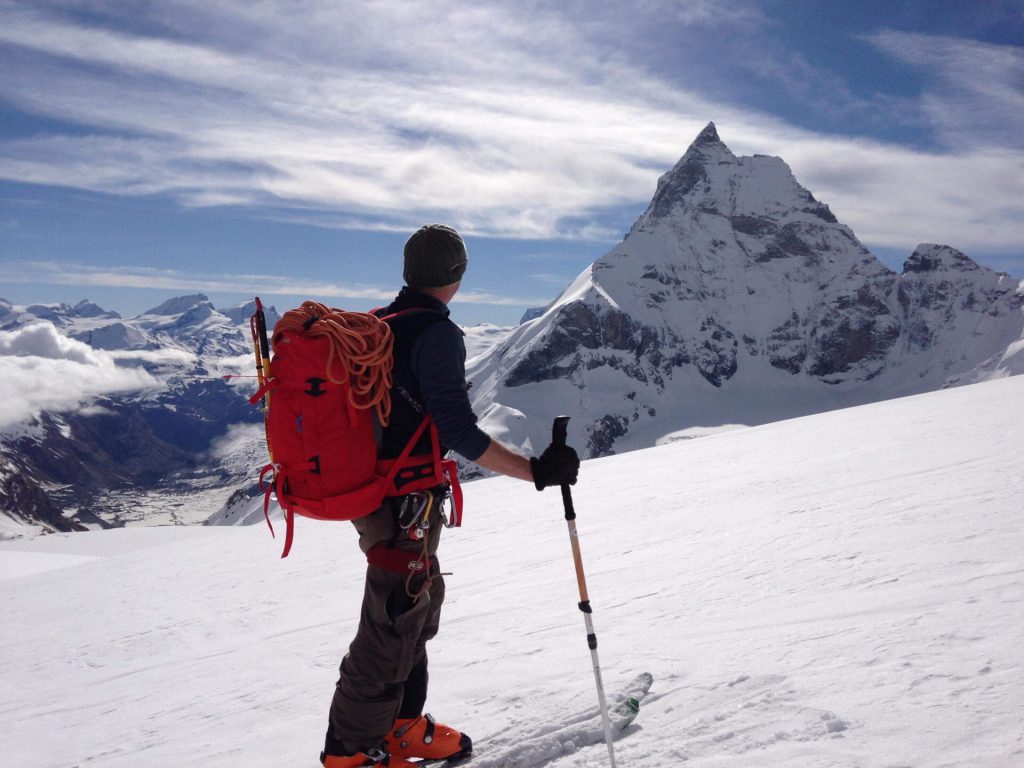 Skitourengehen für Anfänger 6 Skitourengänger blickt auf einen entfernten Berg.