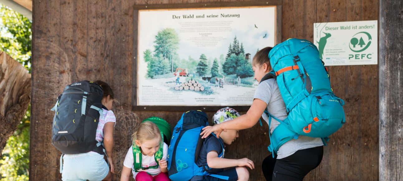 Kinderrucksack packen - Kinder mit ihren Rucksäcken auf einer Bank während eines Wanderausflugs.