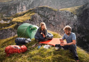 Trekking equipment 10 Trekking equipment - man and woman cooking next to a tent in the mountains.