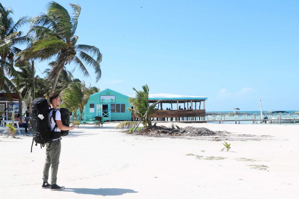 Daniel steht am Strand und wartet auf das Wassertaxi zur Insel Caye Caulker.