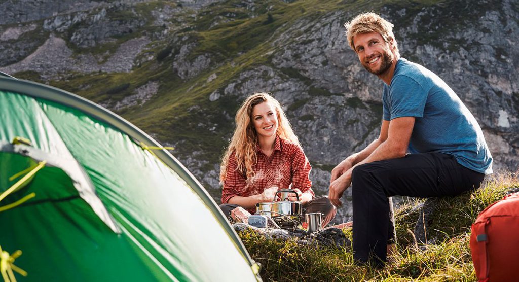 Backpacking hygiene 5 A woman and a man on a trekking tour sitting next to a tent.