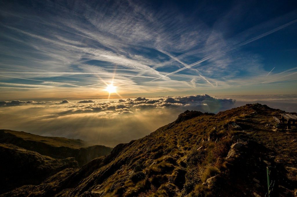 Kondensstreifen am Himmel über den Bergen helfen bei der Bestimmung des Wetters.