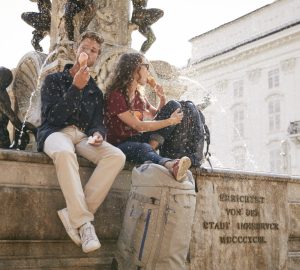 Outdoor City Guide Innsbruck 13 Ein Paar sitzt auf einem Brunnen in Innsbruck und isst ein Eis.