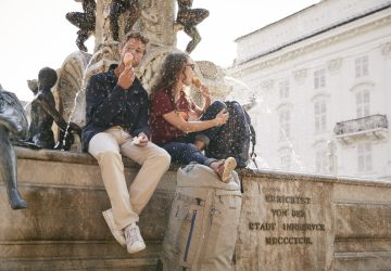 Outdoor City Guide Innsbruck 2 Ein Paar sitzt auf einem Brunnen in Innsbruck und isst ein Eis.