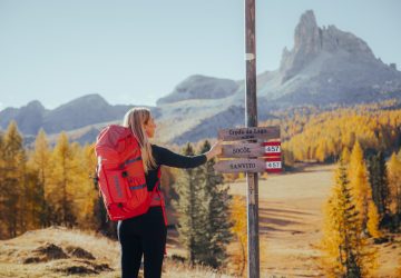 Tourentipp: Herbstwandern in den Dolomiten 4 Mareike stands next to a signpost while hiking in the Dolomites in the fall.