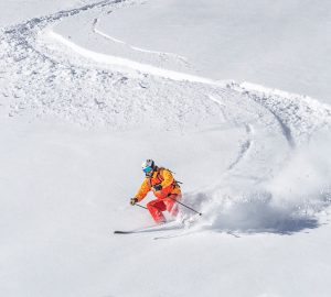 Skitouren und Lawinen 5 Lawinensicherheit Praxistipps. Im Bild: Ein Skifahrer fährt in Schlangenlinien den Berg hinunter.